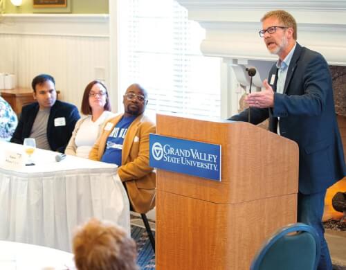 Man stands at a podium in front of a small group of people